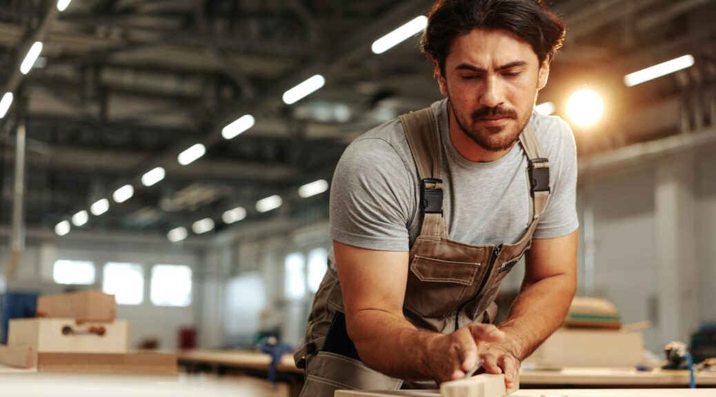 Young carpenter making wood furniture while working in joinery